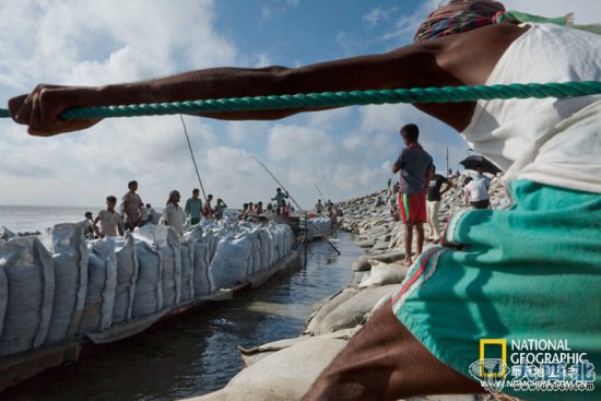 孟加拉国锡拉杰甘杰的人们运来一船船沙袋，用以加固贾木纳河遭洪水侵蚀的河堤。如果融冰导致河水泛滥，这种临时补救措施将会越来越普遍。